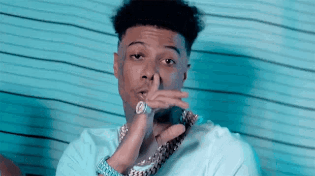 a man with a watch on his wrist is covering his mouth with his finger .