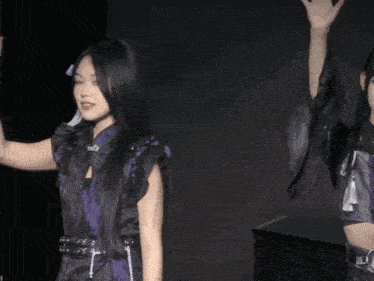 a woman in a purple and black outfit holds her hand up