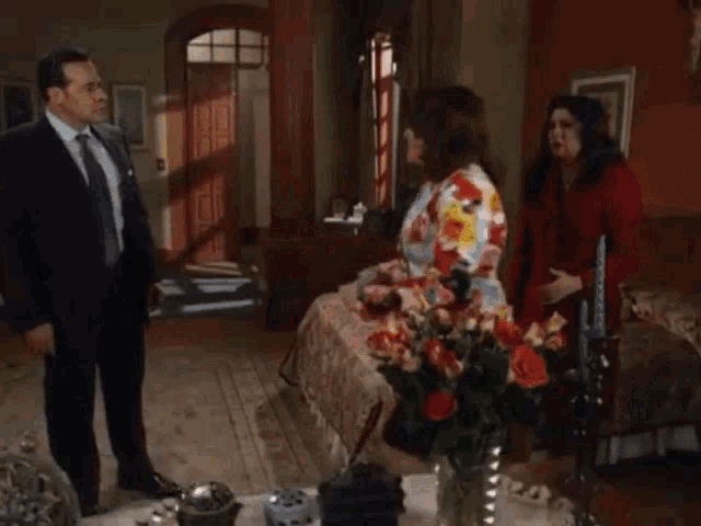 a man and two women are standing in a living room
