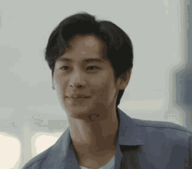 a young man in a blue shirt is smiling and looking at the camera