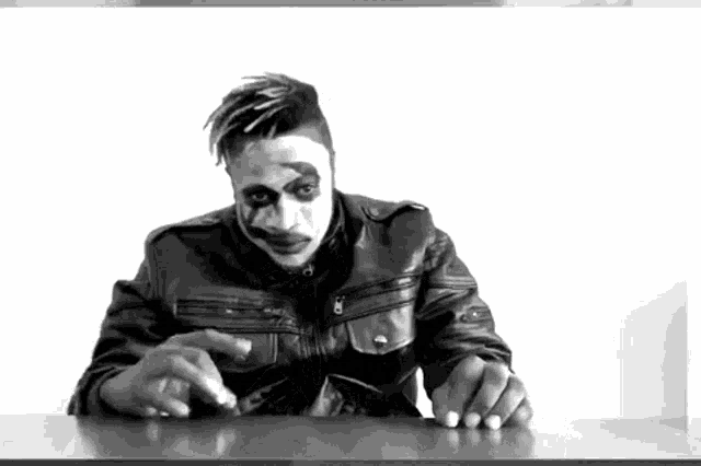a black and white photo of a man wearing a leather jacket and face paint