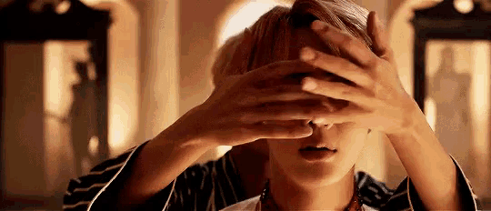 a woman is covering her eyes with her hands .