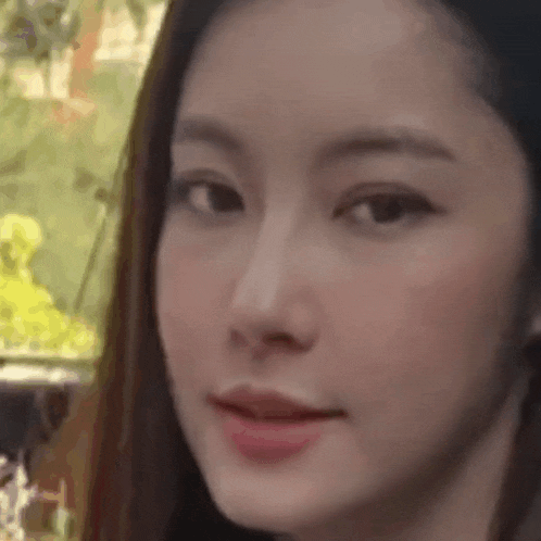 a close up of a woman 's face with a blurry background and trees in the background .