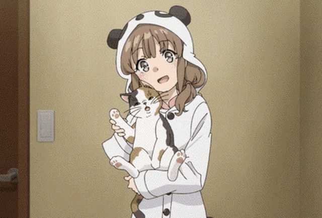 a girl wearing a panda hat is holding a cat .