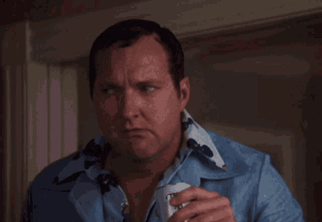 a man in a blue shirt is holding a can of bud light beer