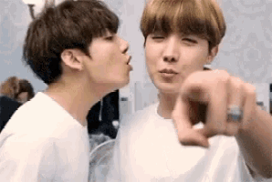 two young men are kissing each other and pointing at each other .