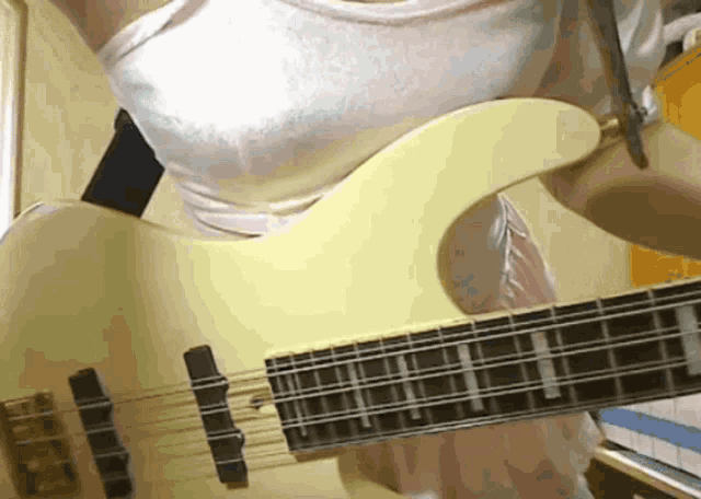 a woman in a white tank top is holding a white guitar