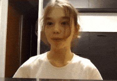 a young girl wearing a white shirt is looking at the camera