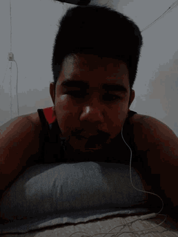 a young man laying on a pillow with headphones on his ears