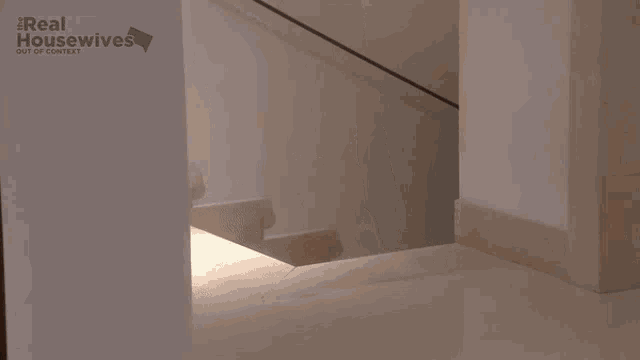 a woman walking down a set of stairs with a real housewives logo in the background