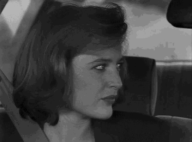 a black and white photo of a woman in a car