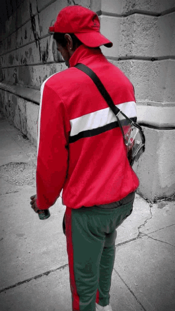 a man wearing a red jacket and green pants is walking down a sidewalk