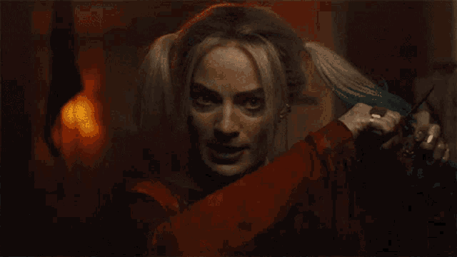 harley quinn is holding a pair of scissors and a knife in her hand .