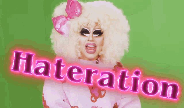 a drag queen is wearing a pink sweater with the word hateration