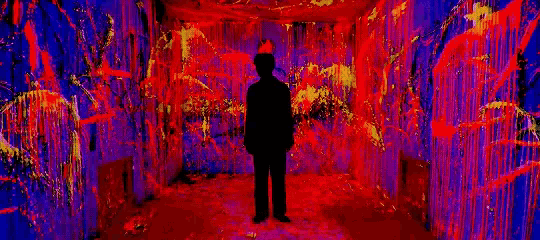 a silhouette of a man standing in a room with purple and red walls