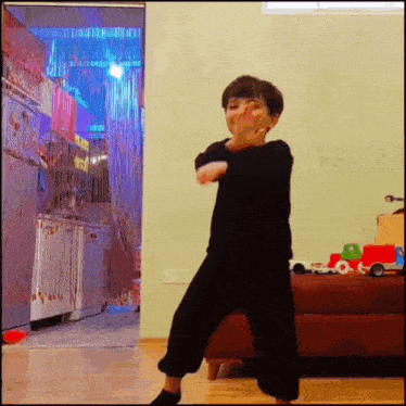 a young boy in a black shirt is dancing in a room