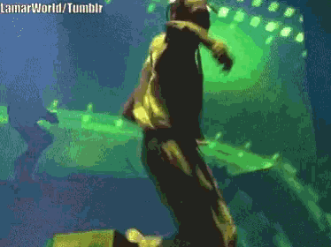 a man is kneeling down on a stage with a green light behind him and the words lamarworld tumblr visible