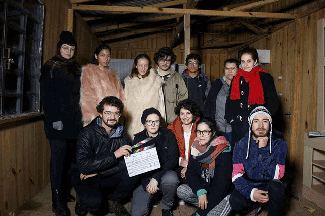 a group of people posing for a picture with one man holding a clapper board that says ' a ' on the bottom