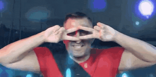 a man is making a peace sign with his hands in front of his eyes .