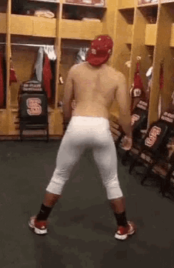 a shirtless baseball player is dancing in a locker room