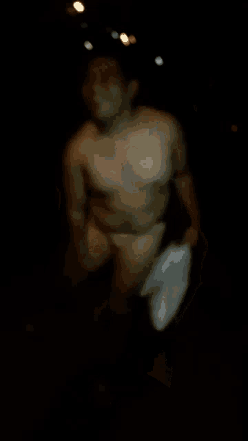 a naked man walking in the dark with a bag in his hand