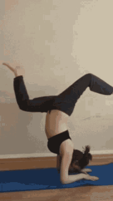 a pregnant woman is doing a handstand on a blue mat .