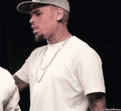 a man wearing a hat and a white t-shirt is standing in front of a black background .