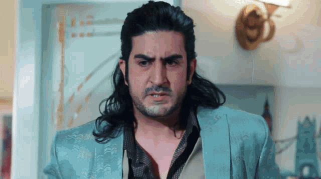 a man with long hair and a beard wears a blue jacket