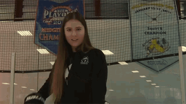 a girl is holding a hockey stick in front of a banner that says ' the playoffs ' on it