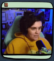 a woman wearing a yellow hoodie is sitting in a chair with a microphone .