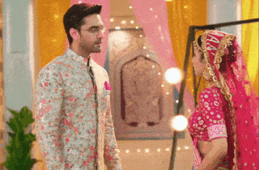 a bride and groom are standing next to each other and the bride is wearing a pink dress