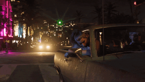 a woman is leaning out of a car window at night .