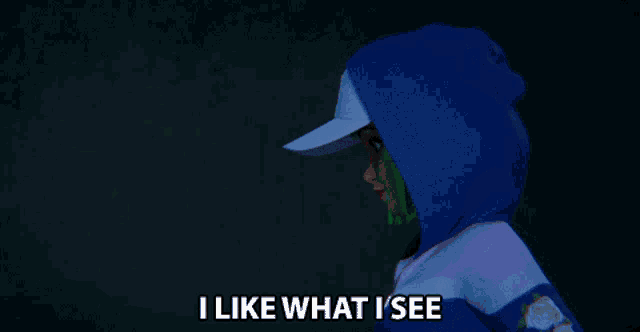 a barbie doll with green hair is wearing a blue hoodie and a white hat and says i like what i see