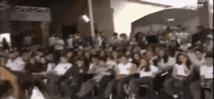 a large group of people are sitting in a room watching a presentation .