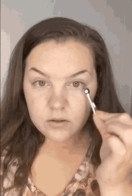 a woman is applying eye shadow to her eye with a small brush .