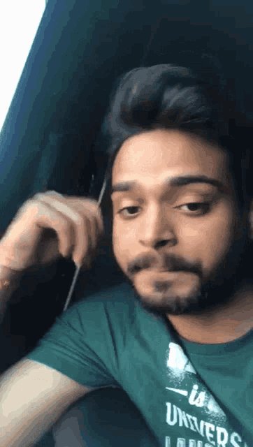 a man with a beard is wearing a green shirt that says ' univers ' on it