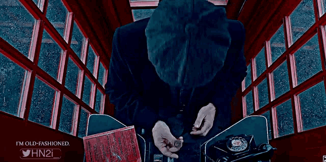 a man in a suit smoking a cigar in a red phone booth