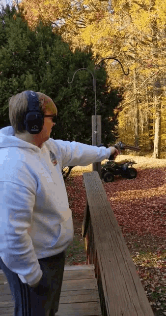a man wearing ear muffs is pointing a gun at something