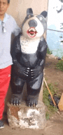 a man is standing next to a statue of a bear with a funny face .