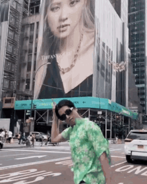 a man in a green shirt is standing in front of a billboard of a woman .