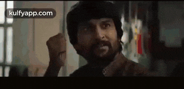 a man with a beard is making a funny face while standing in a room .