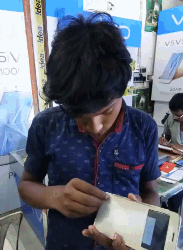 a young man looks at a cell phone in front of a sign that says 5v 100