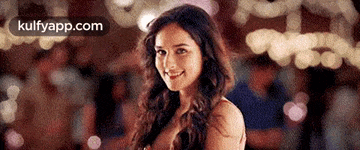 a woman is smiling and looking at the camera while standing in front of a crowd .