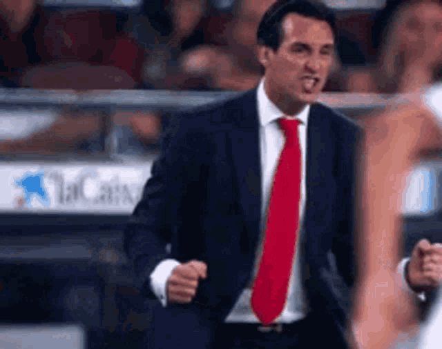 a man in a suit and red tie is yelling at a player