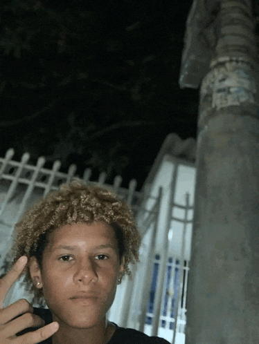 a young man stands in front of a fence and a pole with a sticker on it that says ' rescue '