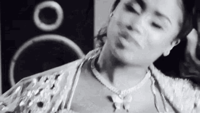 a black and white photo of a woman wearing a necklace .