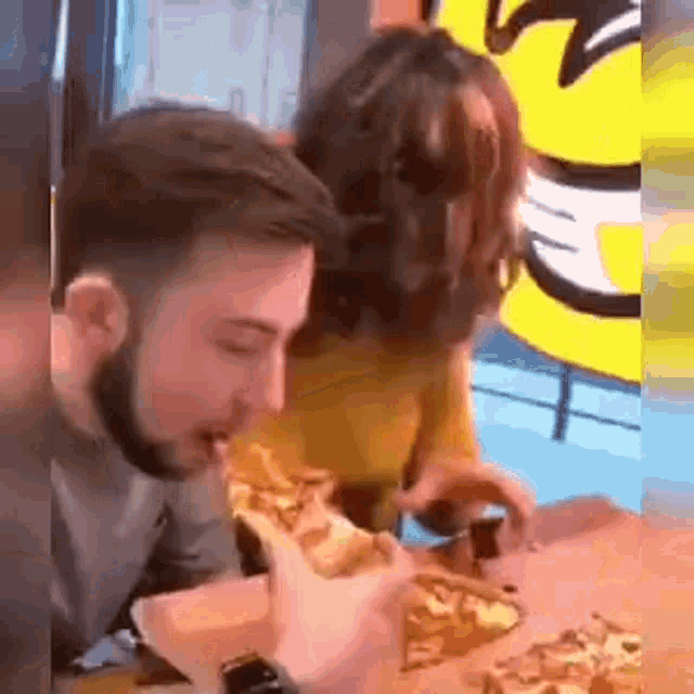 a man and a woman are eating pizza at a table .
