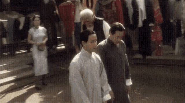 a group of men are walking down a street in front of a store .