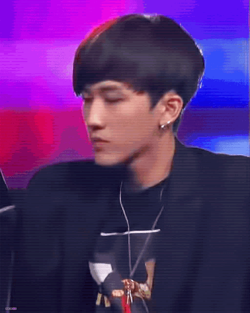 a young man wearing a black jacket and a black shirt with a necklace around his neck