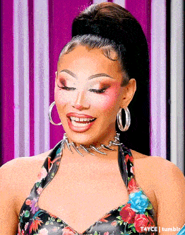 the woman is wearing a floral dress and hoop earrings and smiling .